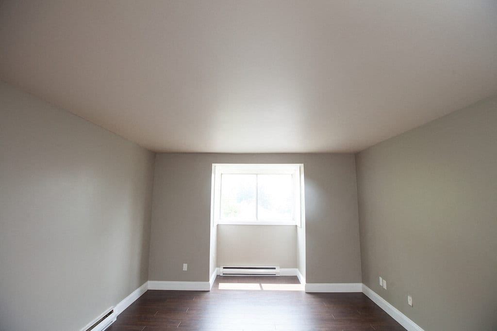 Bedroom with a wide window and plank flooring